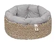 Ein ovales Körbchen, geflochten aus Seegras und ausgekleidet mit einem fluffigen Polster mit Baumwollbezug in hellgrau.
