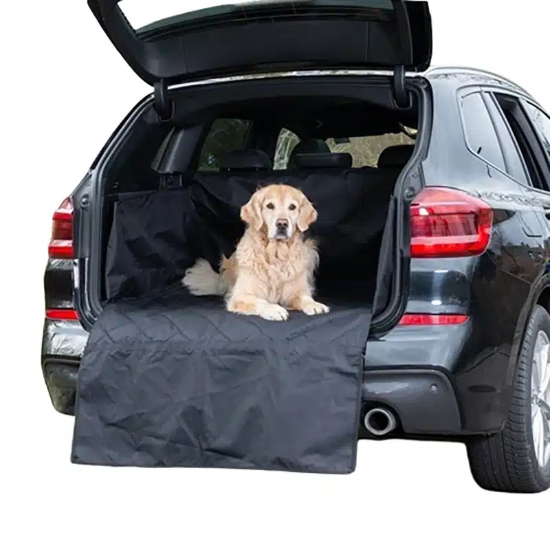 Das Bild zeigt einen Golden Retriever, der artig im geöffneten Kofferraum eines SUV wartet. Der Kofferraum ist mit einer robusten, abgesteppten Hundedecke aus Oxfordgewebe ausgekleidet, die auch alle Seiten und die Stoßstange bedeckt.